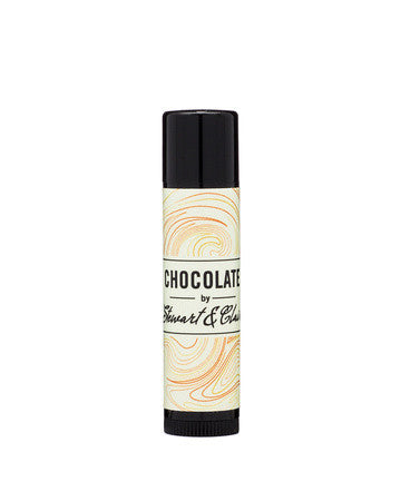 An image of a .15 ounce tube of lip balm. The tube is black plastic. The label is off-white with has a swirly pattern that has orange, brown, and slightly reddish lines. In the center, it says, "Chocolate by Stewart & Claire." The letters are black. The background is white.