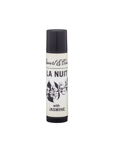 An image of a .15 ounce lip balm tube in black plastic. The tube has a an off-white label that says Stewart & Claire in black script. Then La Nuit in large black letters. Below that is a black and white illustration of jasmine and below it, the text says, with jasmine. It is on a white background. 
