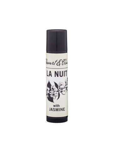 An image of a .15 ounce lip balm tube in black plastic. The tube has a an off-white label that says Stewart & Claire in black script. Then La Nuit in large black letters. Below that is a black and white illustration of jasmine and below it, the text says, with jasmine. It is on a white background.