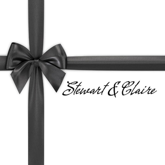 An image of a white square that looks like a gift tied with a black bow. The box says Stewart & Claire with script black letters.
