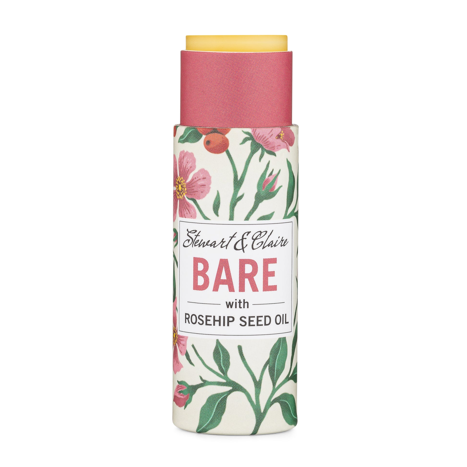 A .3 ounce paperboard tube of lip balm. The tube is off-white with illustrations of roses and rose hips. The tube is open at the top to reveal the balm, which is slightly pushed up. There is a white square on the tube with text that shows Stewart & Claire in script. It says Bare it large pink letters then with rosehip seed oil in black letters. It is on a white background. 