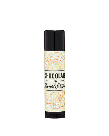 An image of a .15 ounce tube of lip balm. The tube is black plastic. The label is off-white with has a swirly pattern that has orange, brown, and slightly reddish lines. In the center, it says, "Chocolate by Stewart & Claire." The letters are black. The background is white. 
