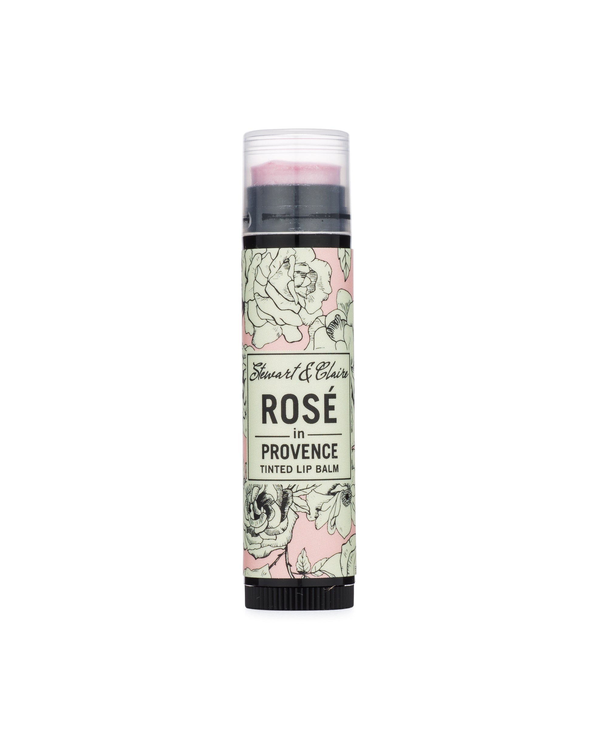 An image of a .15 ounce black plastic tube with a clear cap. Through the cap, you can see a lip balm that is a frosty pink. The tube has a label in pink, black, and white with a rose pattern. In the center of the balm is an off-white square that says Stewart & Claire in black script and then Rosé in Provence, Tinted Lip Balm underneath. 