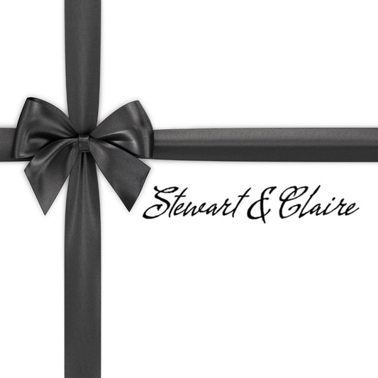 An image of a white square that looks like a gift tied with a black bow. The box says Stewart & Claire with script black letters. 